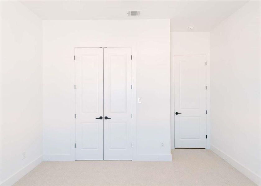 Unfurnished bedroom featuring light carpet and a closet