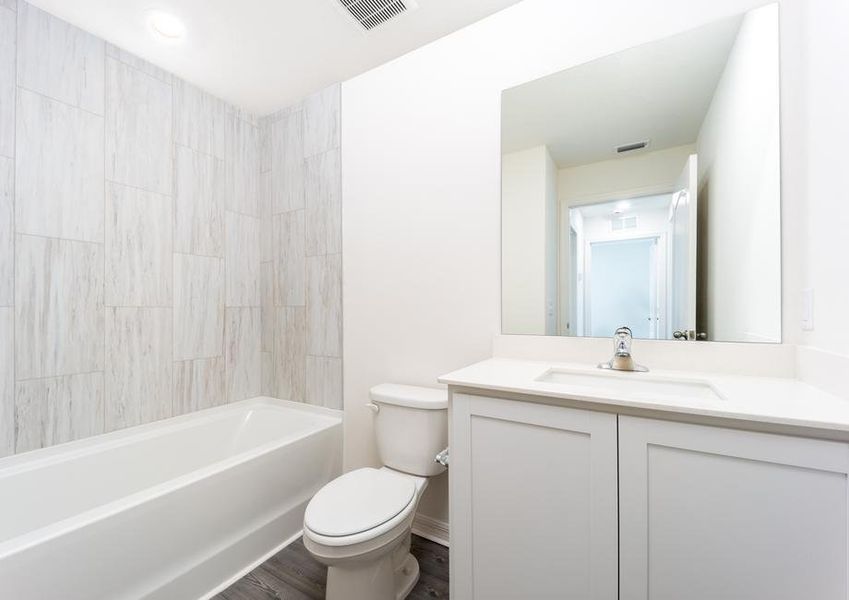 Tile detail surrounds the shower/tub combination in the secondary bathroom