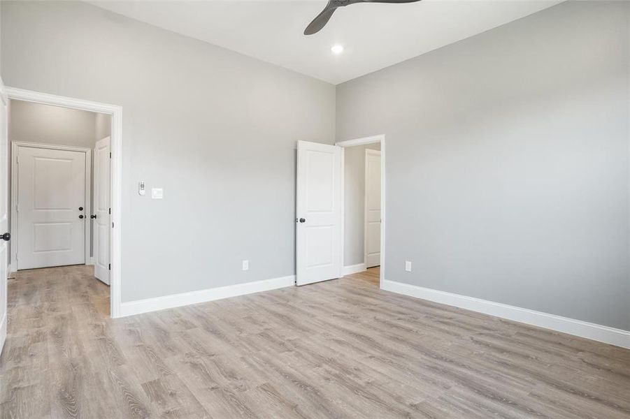 Empty room with light hardwood / wood-style floors, a high ceiling, and ceiling fan