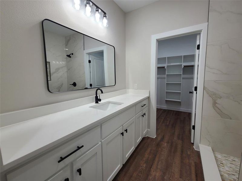 Primary Bathroom with hardwood / wood-style floors, tiled shower, and vanity