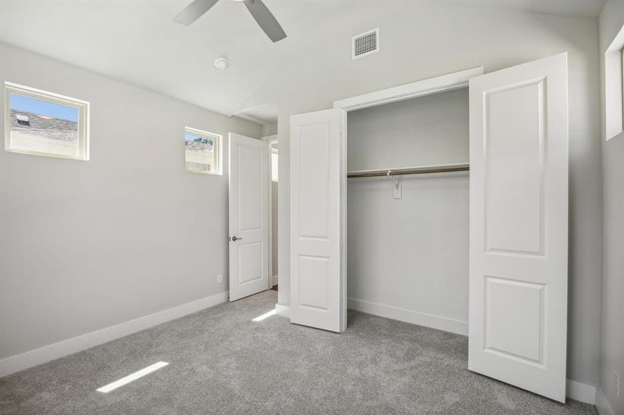 Unfurnished bedroom featuring multiple windows, vaulted ceiling, ceiling fan, and a closet