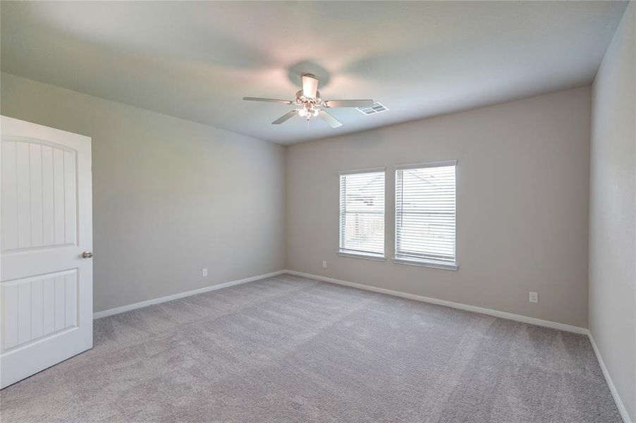 This spacious bedroom  it’s well-lit by a flush mount ceiling light, creating a bright and versatile space.