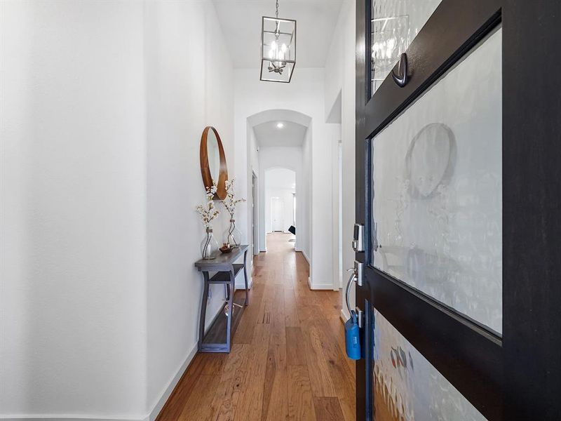 Gorgeous entry welcomes you with rich wood flooring, beautifully contrasting with soft, light wall colors. The high ceilings amplify the sense of space and sophistication, creating an inviting atmosphere that sets the tone for the rest of the home.