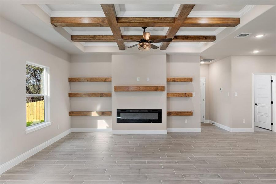 Unfurnished living room featuring beam ceiling, coffered ceiling, and ceiling fan
