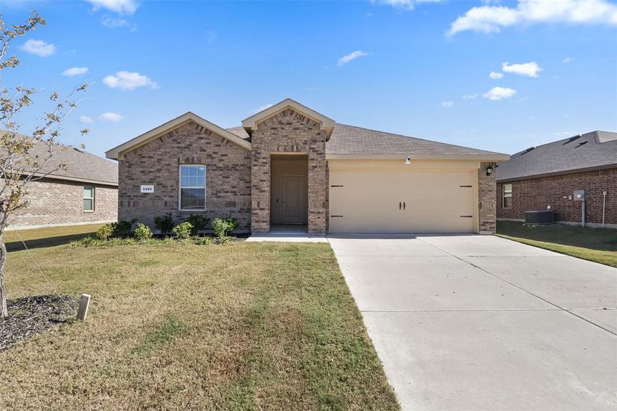 View of front of property featuring a garage, central air condition unit, and a front lawn