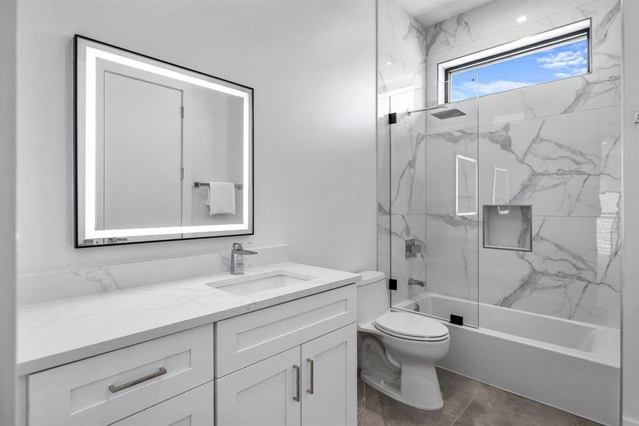 Full bathroom with toilet, tiled shower / bath combo, and vanity