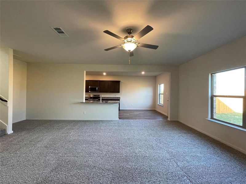 Unfurnished living room with ceiling fan and dark carpet