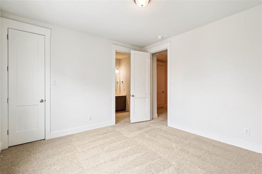 Unfurnished bedroom featuring light colored carpet and ensuite bath