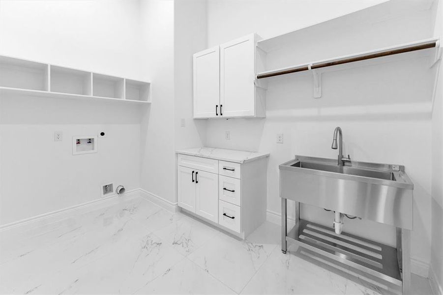 Large laundry room with built-in storage, quartz countertop and free-standing stainless steel sink.