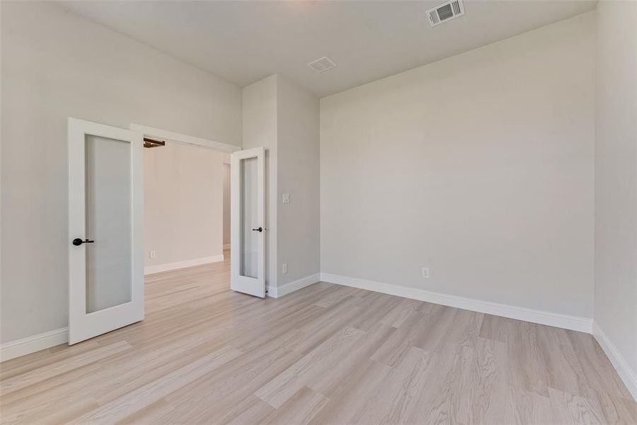 Empty room with light wood-type flooring and french doors