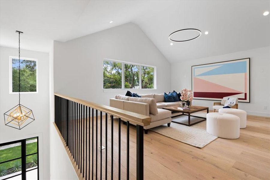 Living room featuring an inviting chandelier, high vaulted ceiling, hardwood / wood-style flooring, and a healthy amount of sunlight