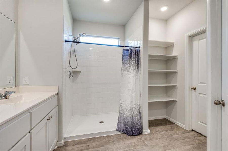 Bathroom featuring hardwood / wood-style flooring, walk in shower, and vanity