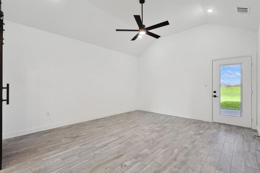 Spare room featuring lofted ceiling, ceiling fan, and light hardwood / wood-style floors