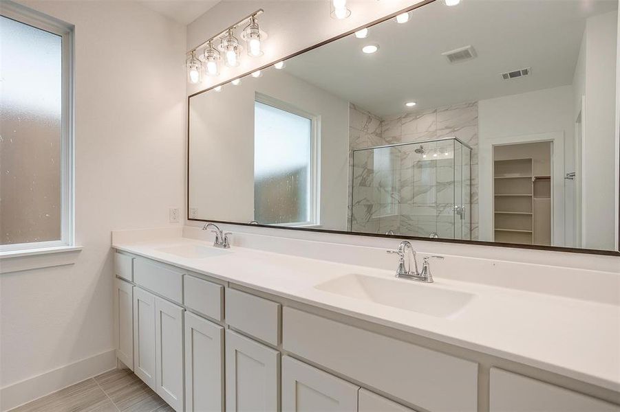 Bathroom featuring walk in shower, tile flooring, and dual bowl vanity