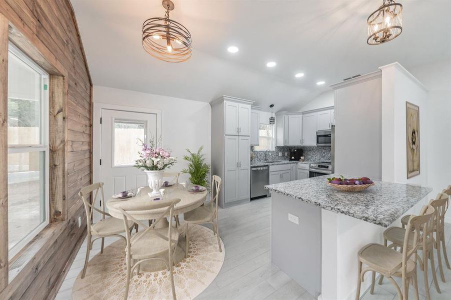 Kitchen featuring decorative light fixtures, vaulted ceiling, and stainless steel appliances