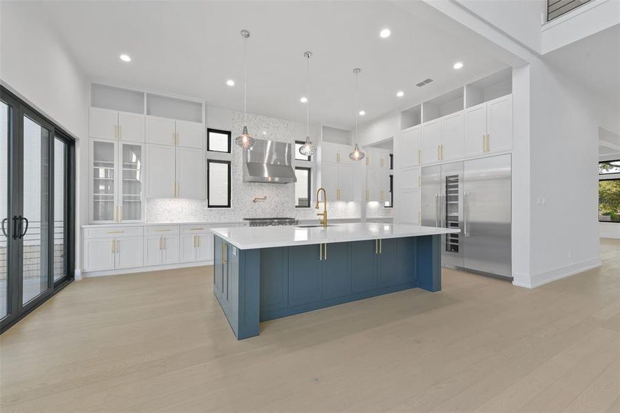 The kitchen is a chef's dream with central island, breakfast bar and sleek integrated appliances. Quartz countertops and custom cabinetry with unlacquered brass hardware complete the kitchen.