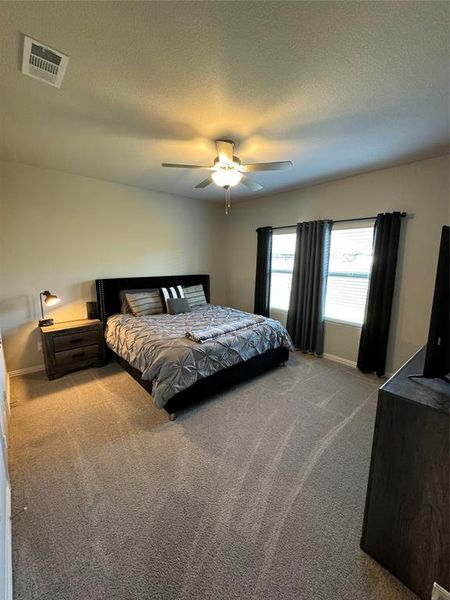 Carpeted bedroom with a textured ceiling and ceiling fan