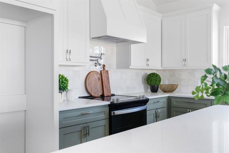 Kitchen featuring stainless steel range with electric stovetop, white cabinets, custom range hood, and gray cabinetry