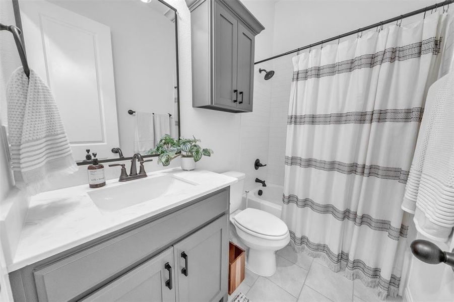 Full bathroom with toilet, vanity, shower / bath combo with shower curtain, and tile patterned flooring