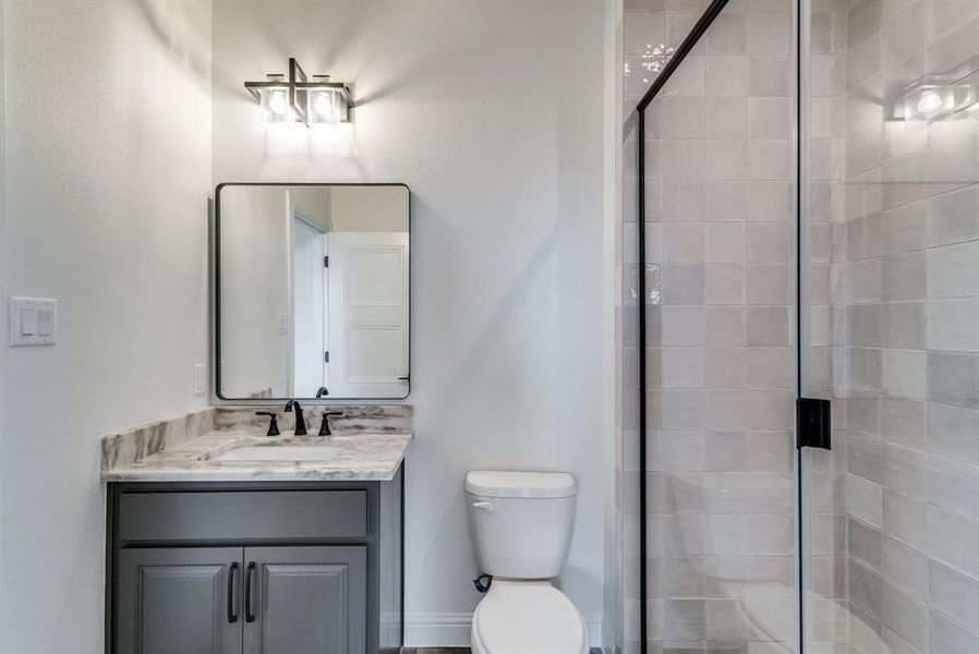 Bathroom featuring vanity, a shower with shower door, and toilet