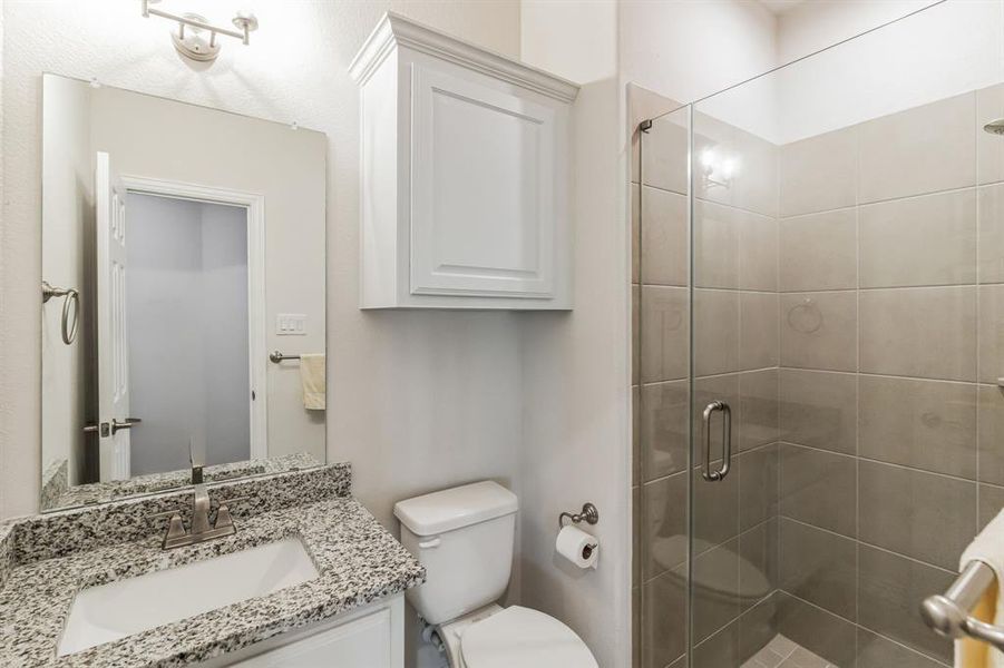 Bathroom with vanity, a shower with door, and toilet