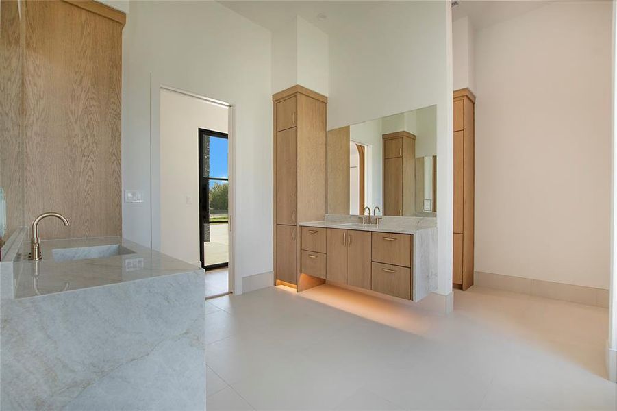 Primary Bathroom with a high ceiling, tile patterned floors, vanity, and a bath