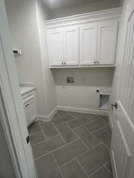 Clothes washing area featuring cabinets, hookup for an electric dryer, washer hookup, and dark tile patterned floors