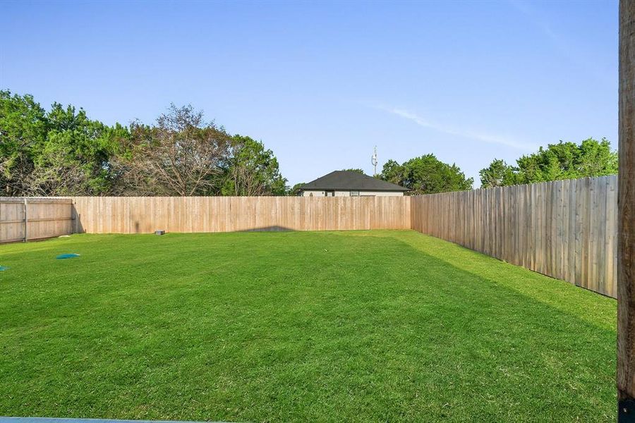 Back of property with a lawn and 6 ft privacy fence