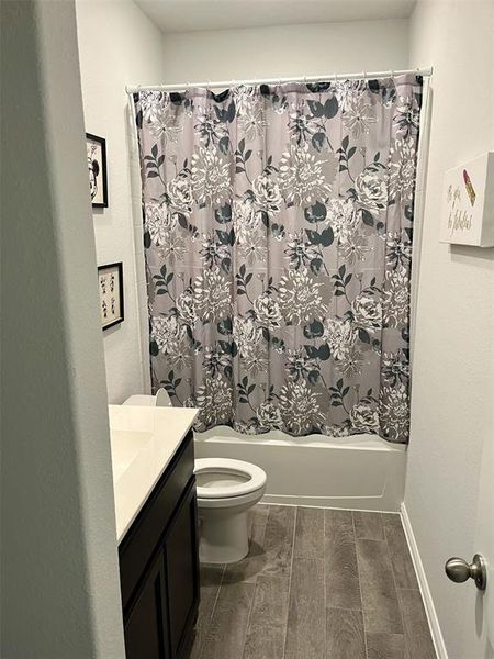 Full bathroom featuring shower / bath combo, vanity, hardwood / wood-style flooring, and toilet