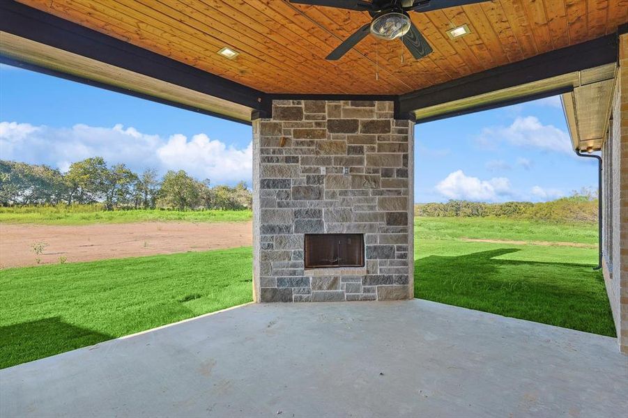 View of patio / terrace with an outdoor stone fireplace and ceiling fan