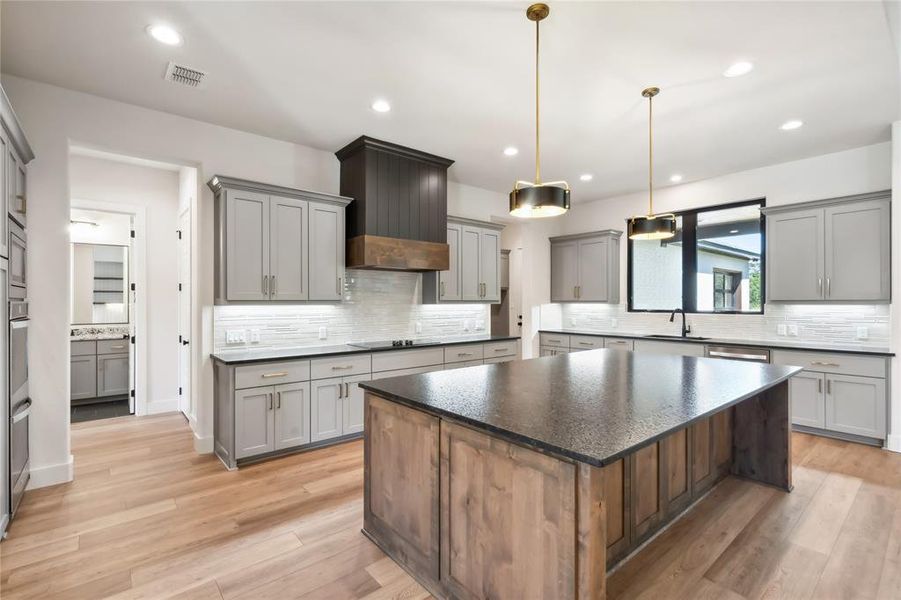 Custom cabinets, decorative lighting fixtures, and granite countertops in the kitchen.