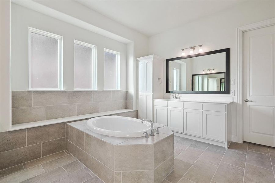 Bathroom with vanity, a relaxing tiled tub, and tile patterned floors