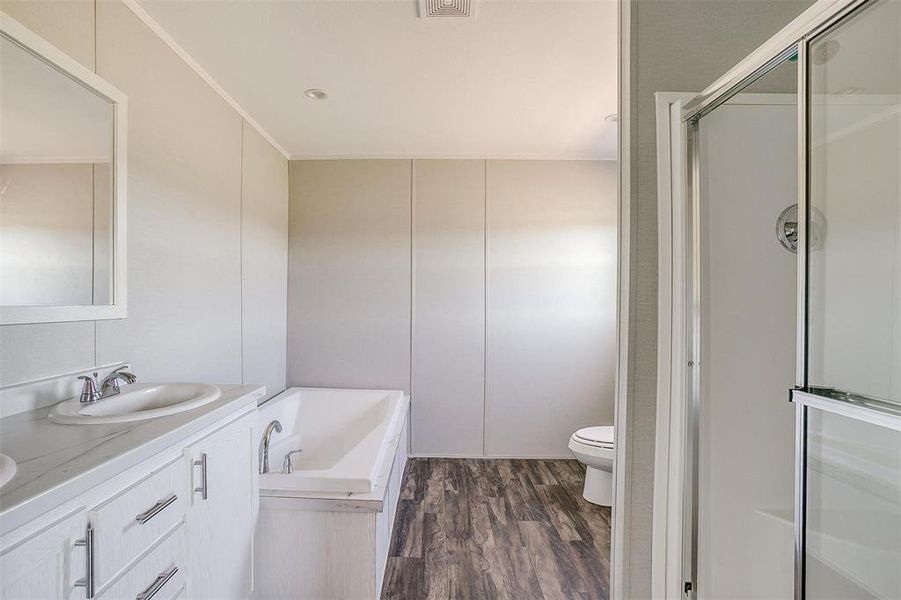 Full bathroom with plus walk in shower, crown molding, toilet, wood-type flooring, and vanity