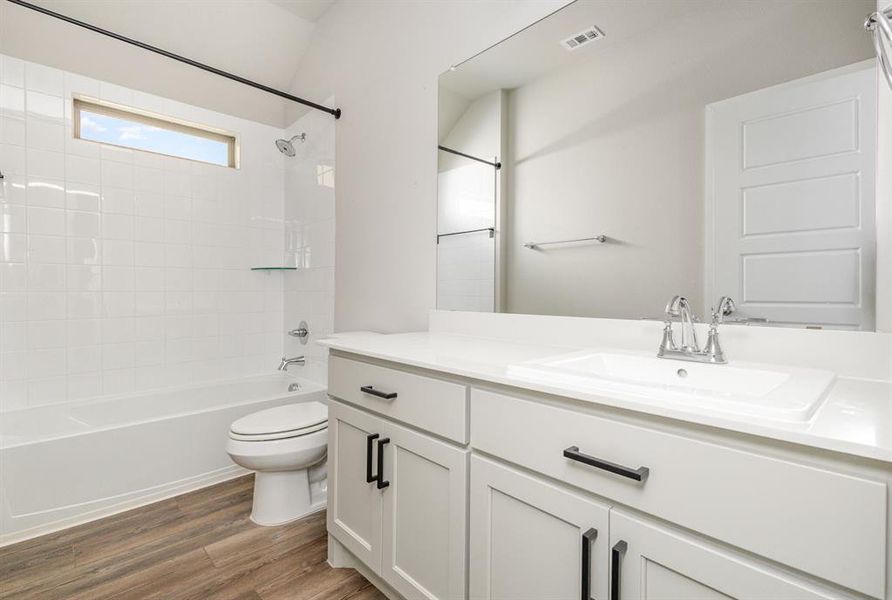 Full bathroom with vanity, hardwood / wood-style flooring, toilet, and tiled shower / bath combo