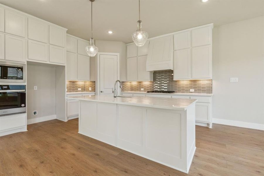 Kitchen featuring white cabinetry, appliances with stainless steel finishes, an island with sink, and light hardwood / wood-style floors