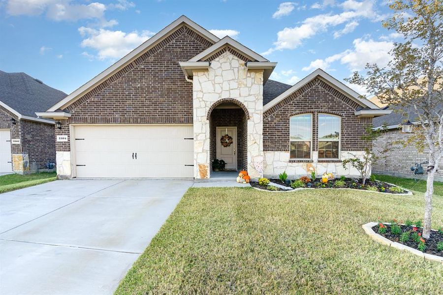 View of front of property featuring a front yard and a garage