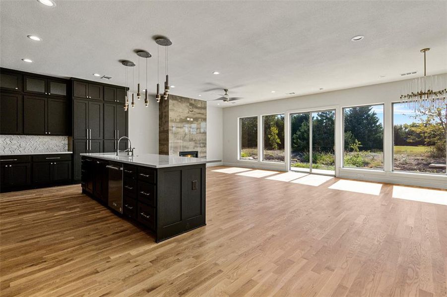 Kitchen featuring light hardwood / wood-style floors, decorative light fixtures, sink, and an island with sink