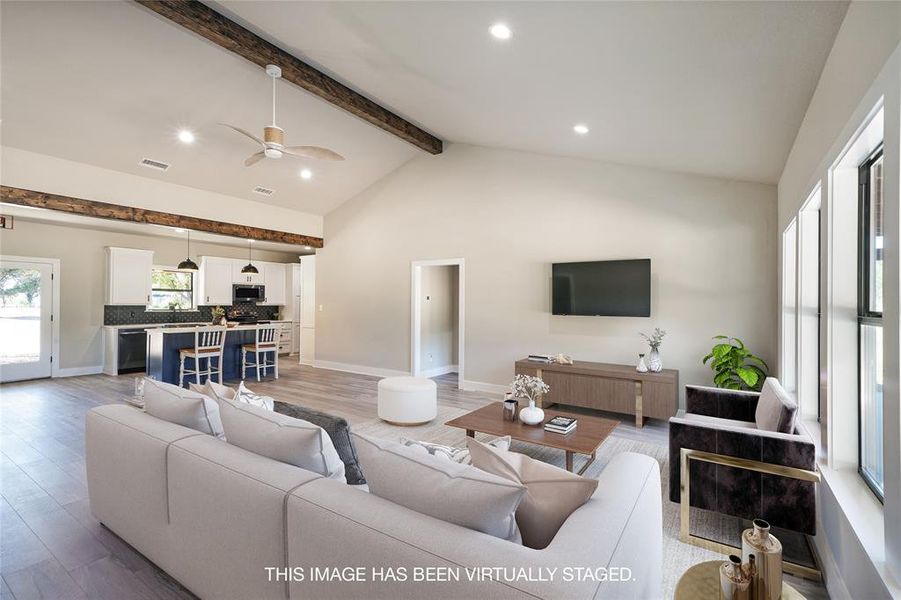 Living room with ceiling fan, lofted ceiling with beams, and light hardwood / wood-style floors