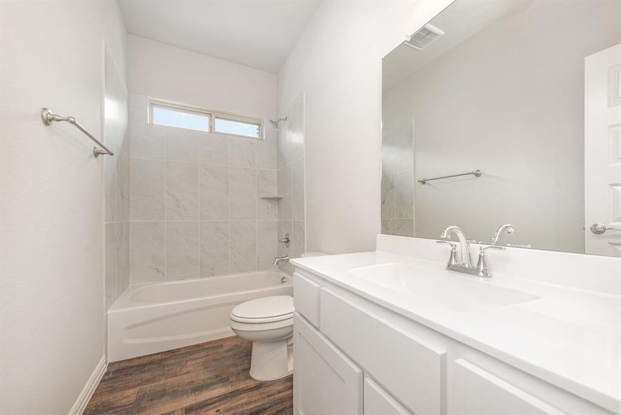 Full bathroom featuring vanity, tiled shower / bath, wood-type flooring, and toilet