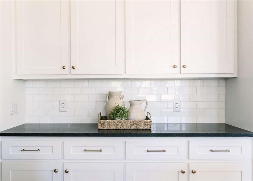 Kitchen featuring decorative backsplash and white cabinetry