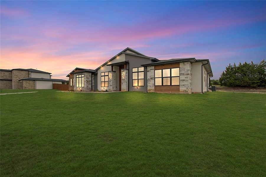 Back house at dusk featuring a yard