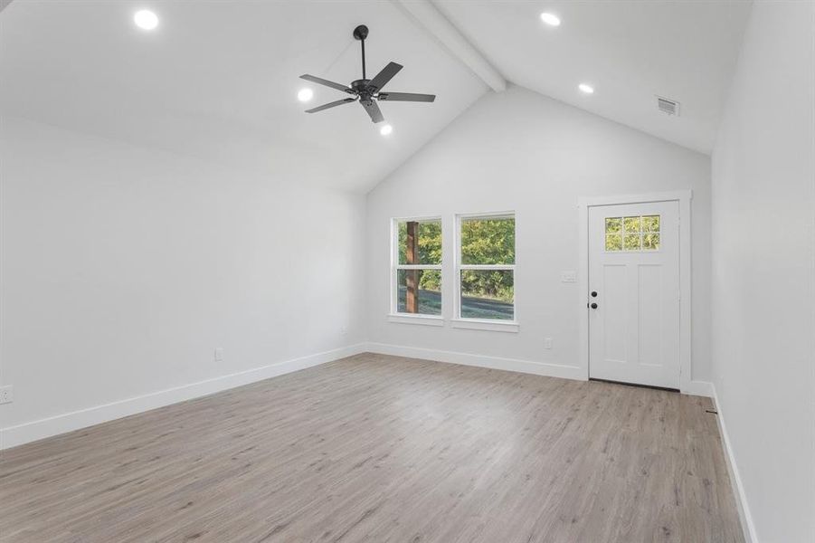 Unfurnished living room with ceiling fan, beam ceiling, light hardwood / wood-style floors, and high vaulted ceiling