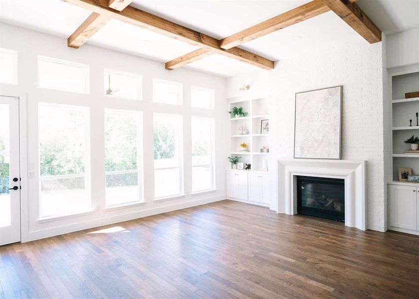 Unfurnished living room featuring beamed ceiling, dark wood-type flooring, and built in features