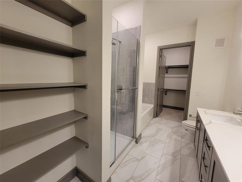 Full bathroom with tile floors, vanity, shower with separate bathtub, and toilet