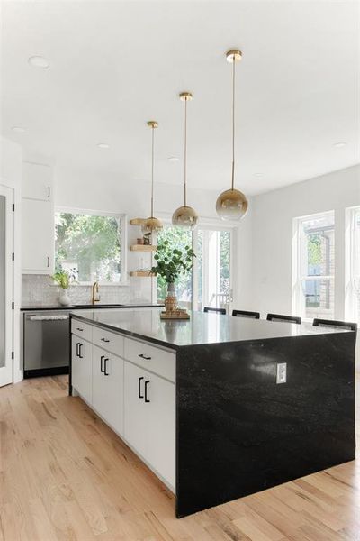 Kitchen with light hardwood / wood-style flooring, tasteful backsplash, dishwasher, decorative light fixtures, and white cabinets
