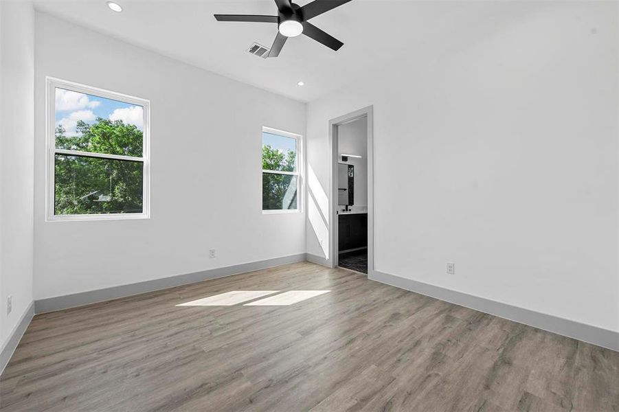 Empty room featuring ceiling fan, hardwood / wood-style floors, and plenty of natural light