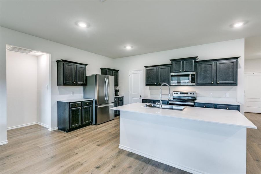 Kitchen with a center island with sink, light wood-type flooring, sink, and appliances with stainless steel finishes