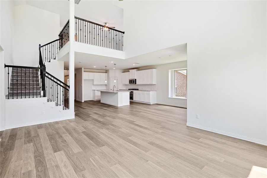 Unfurnished living room featuring light hardwood / wood-style floors, sink, and a high ceiling