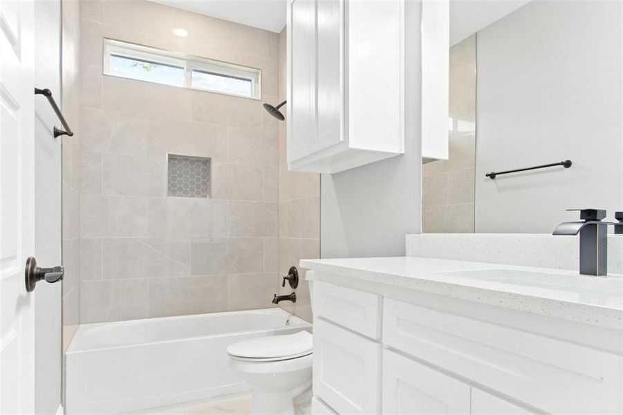 Full bathroom with tiled shower / bath combo, vanity, and toilet