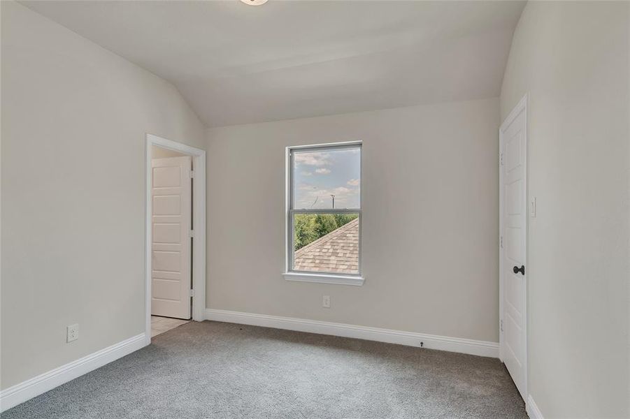 Carpeted spare room featuring lofted ceiling